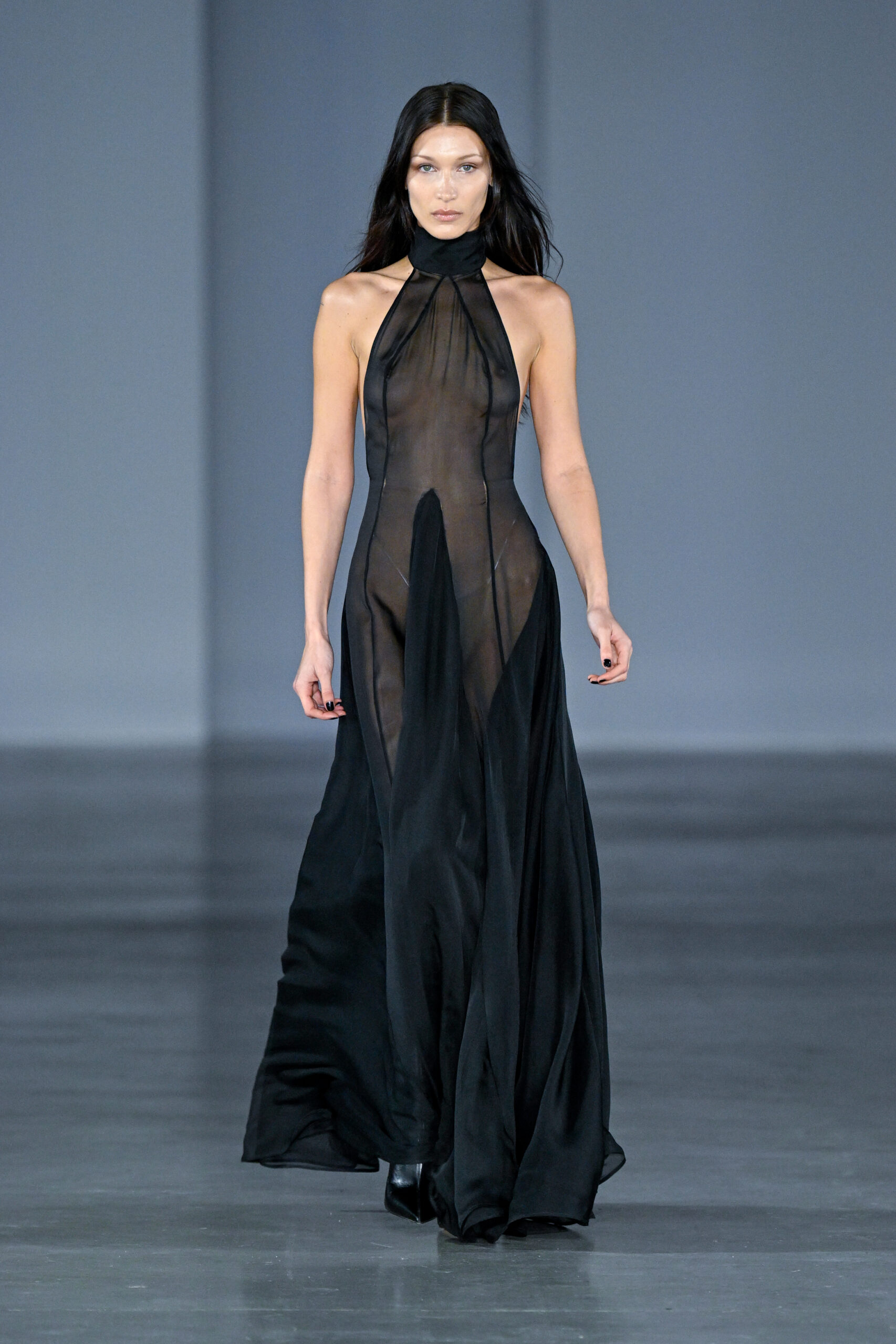 Bella Hadid egy csipkés, fekete átlátszó ruhában sétál a kifutón a Párizsi Fashion Week-en.