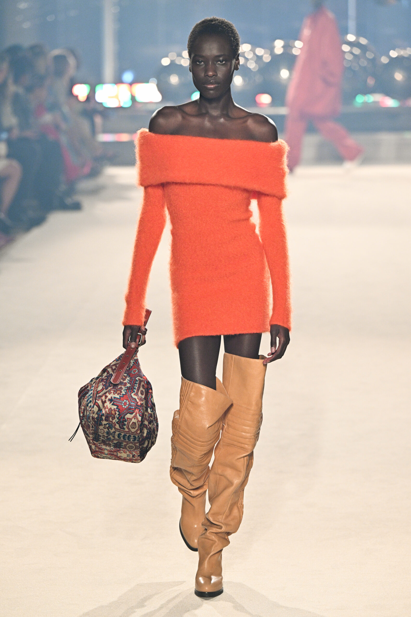 Egy modell narancssárga ruhában sétál a Párizsi Fashion Week kifutóján