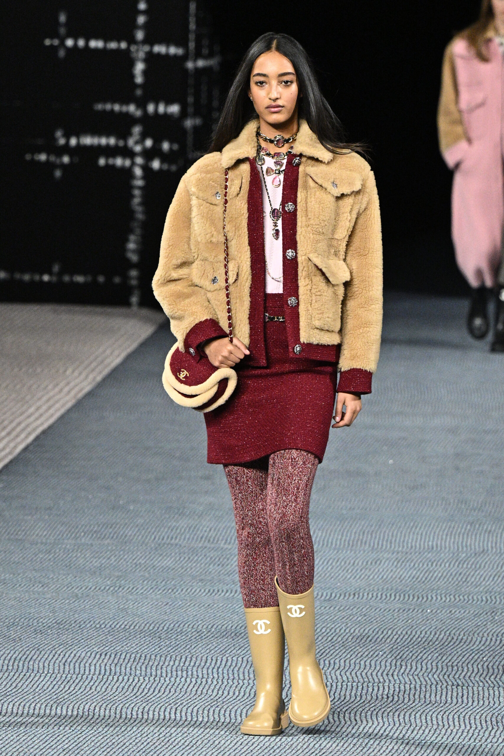 Egy modell szőrmés, sárga kabátban, és egy mustárszínű gumicsizmában sétál a Párizsi Fashion Week kifutóján