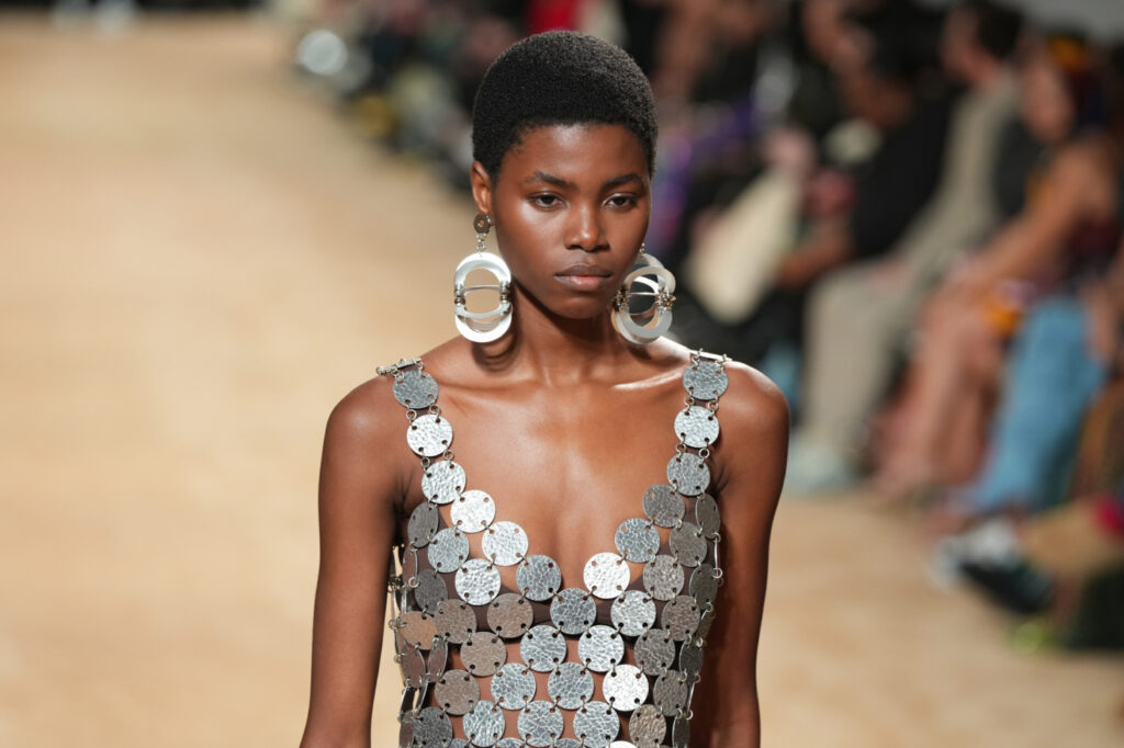 divatos kiegészítők 2024-ben – masszív ezüst fülbevalót és ezüst színű, csillogó ruhát viselő modell