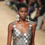 divatos kiegészítők 2024-ben – masszív ezüst fülbevalót és ezüst színű, csillogó ruhát viselő modell