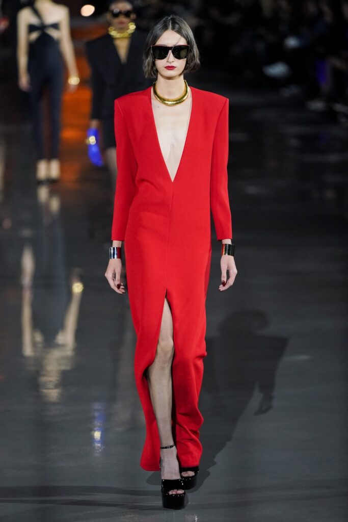 Egy modell mélye dekoltált, piros, kivágott ruhában és platformos szandálban