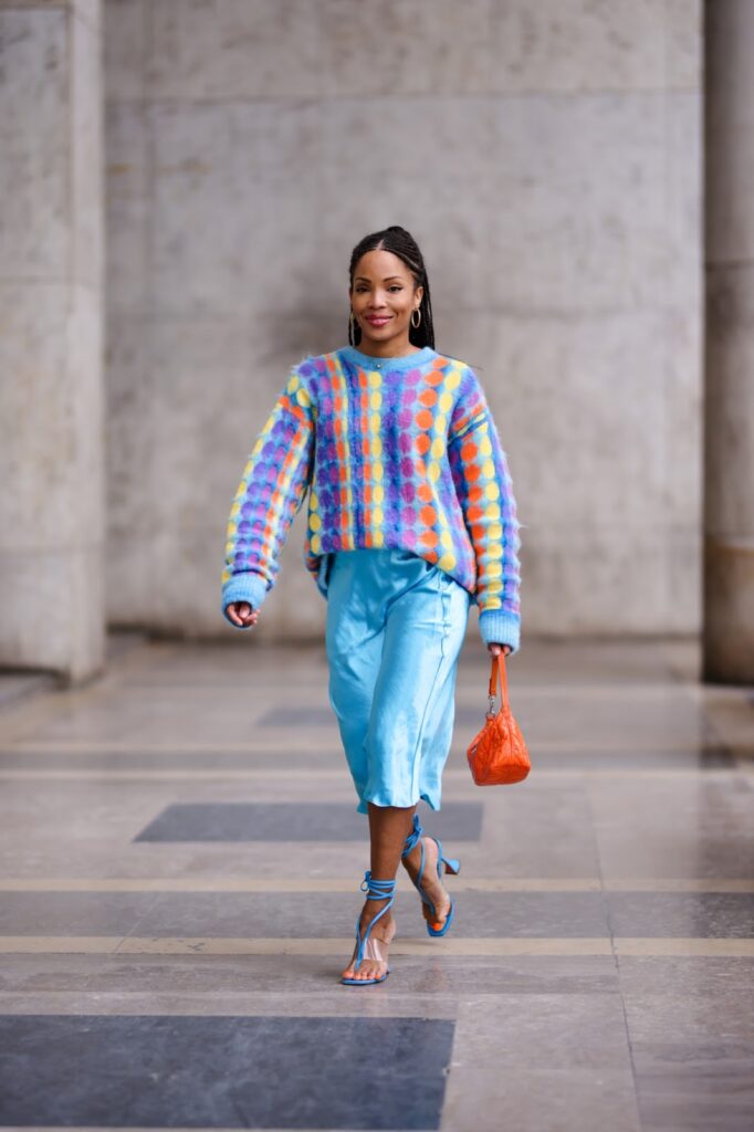 Egy modell szatén szoknyában és színes, mintás pulóverben
