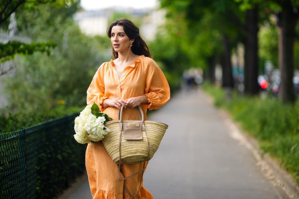 Egy modell narancssárga lenvászon ruhában és kosaras táskával