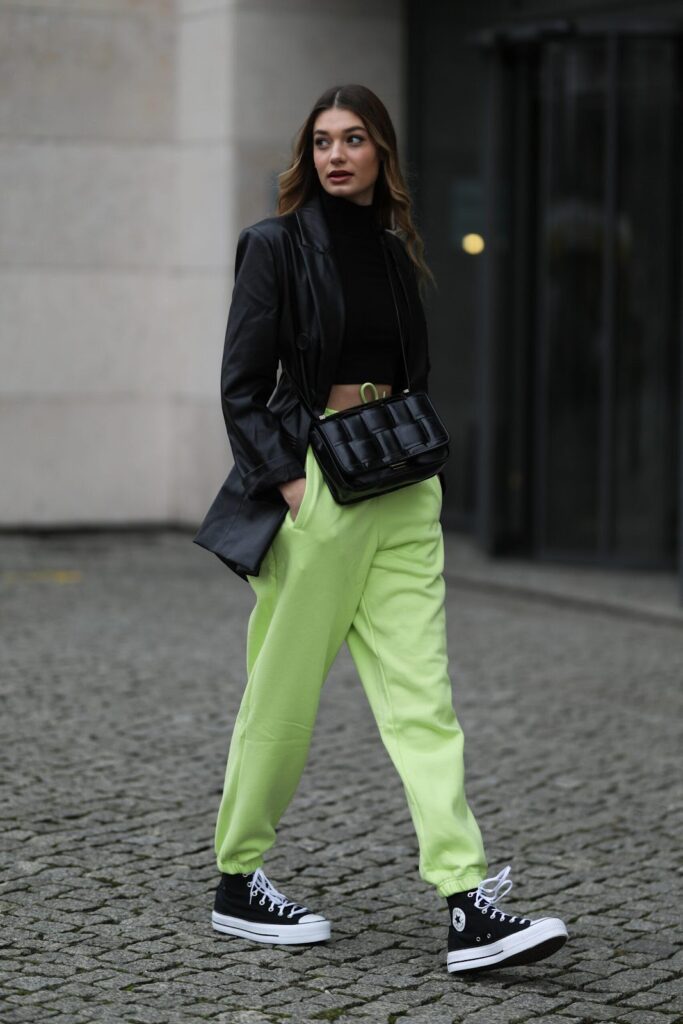 Modell fekete blézerben, zöld nadrágban és platformos Converse cipőben