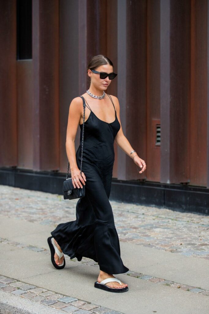 Modell egy platformos vietnámi papucsban és fekete, ujjatlan maxi ruhában