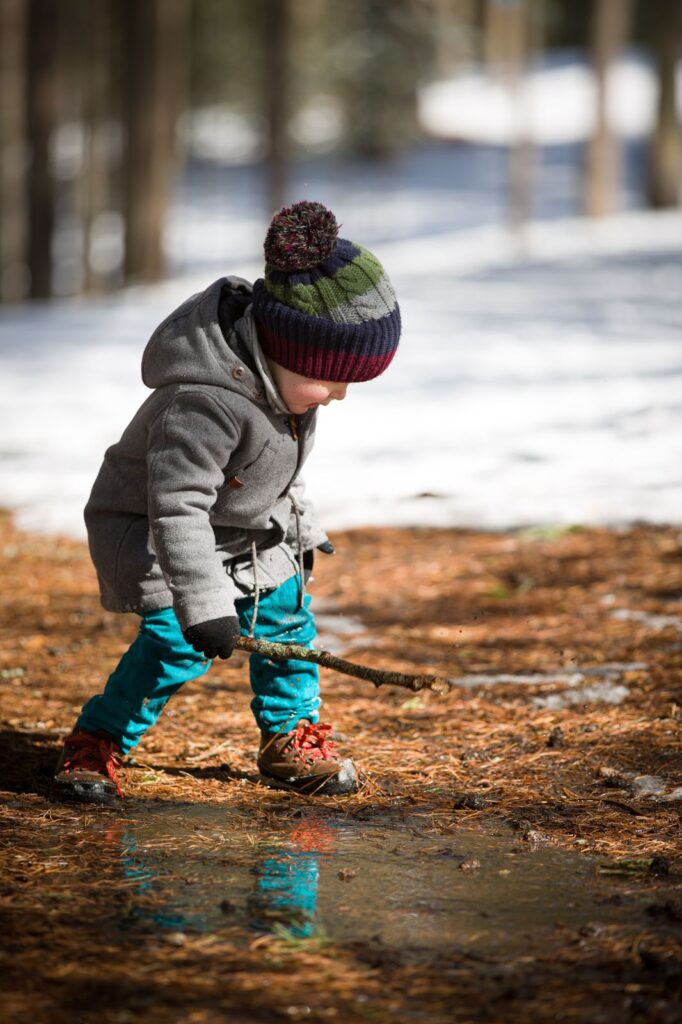 Egy kisfiú egy faággal a kezében sétál