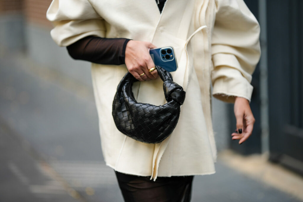 Egy vendég oversized, hosszú ujjú kabátban és egy Bottega Veneta táskával a Milan Fashion Week-en