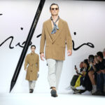 Férfi divat: 2024-es trendek a kifutókón – teveszínű kabátba öltözött modell, kendővel a nyakában