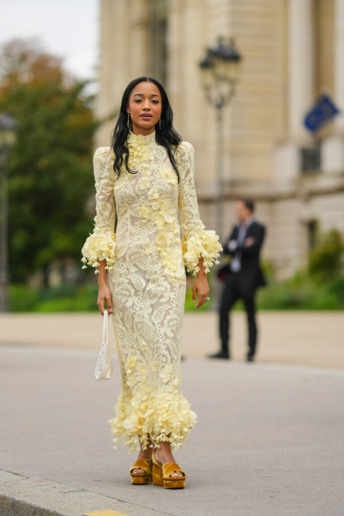 Csipkés, sárga ruhát viselő vendég a Párizsi Divathéten