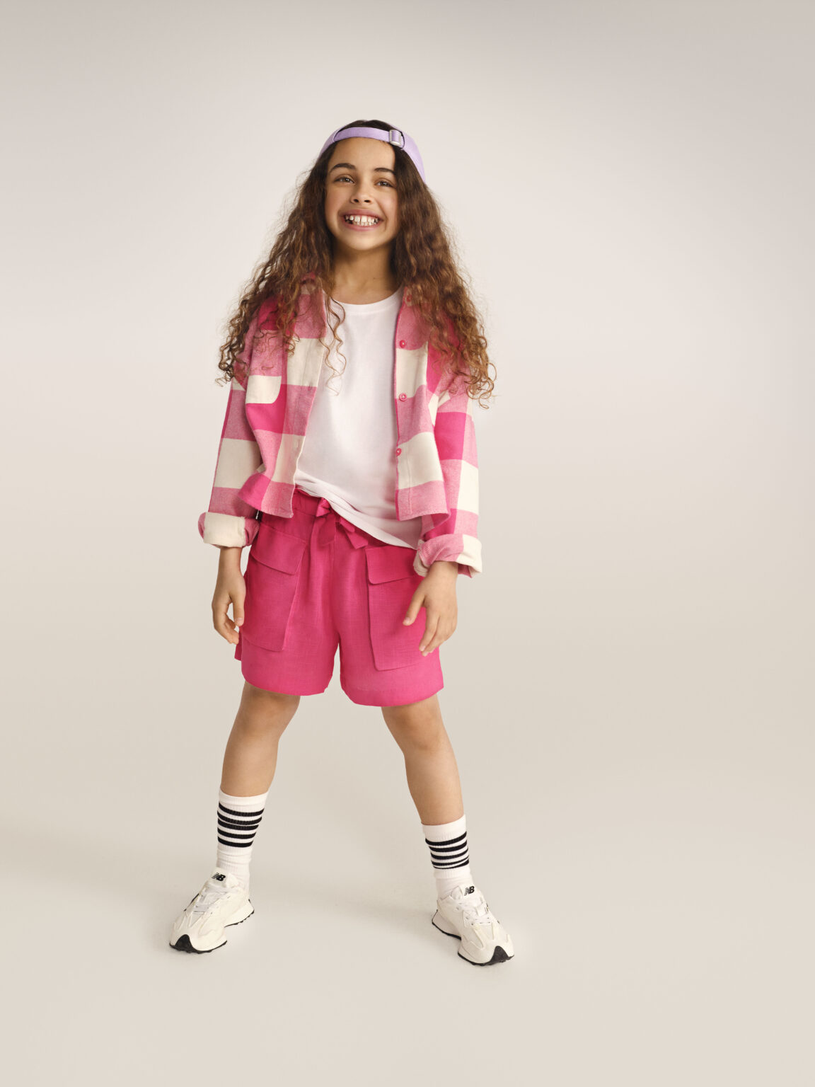 Kockás, rózsaszín felsőt és rózsaszín rövidnadrágot viselő kislány