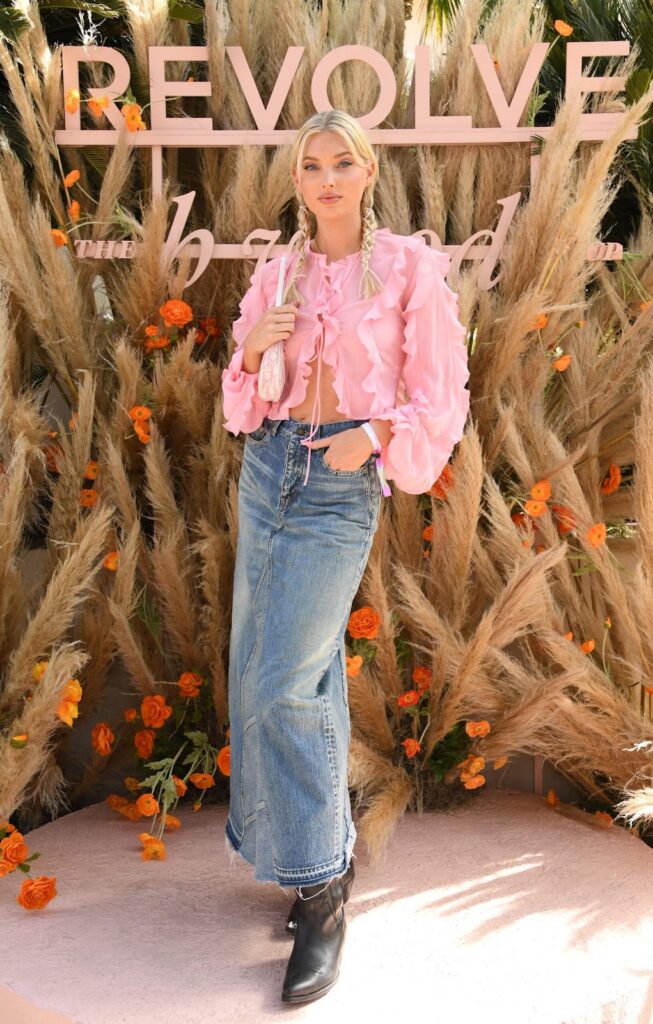 Egy country stílusú, rózsaszín, pufi ujjas blúzból, farmer maxi hosszúságú szoknyából és western csizmából álló fesztiválos outfit
