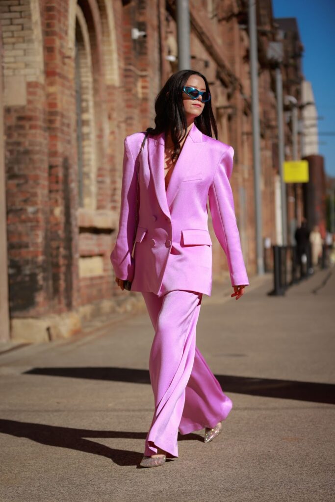 Egy alkalmi, rózsaszín kosztümöt viselő divatos nő