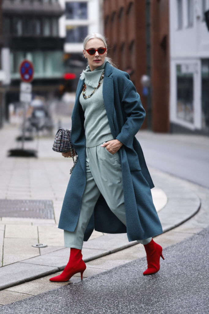 petrolkék kabátot és piros cipőt viselő nő